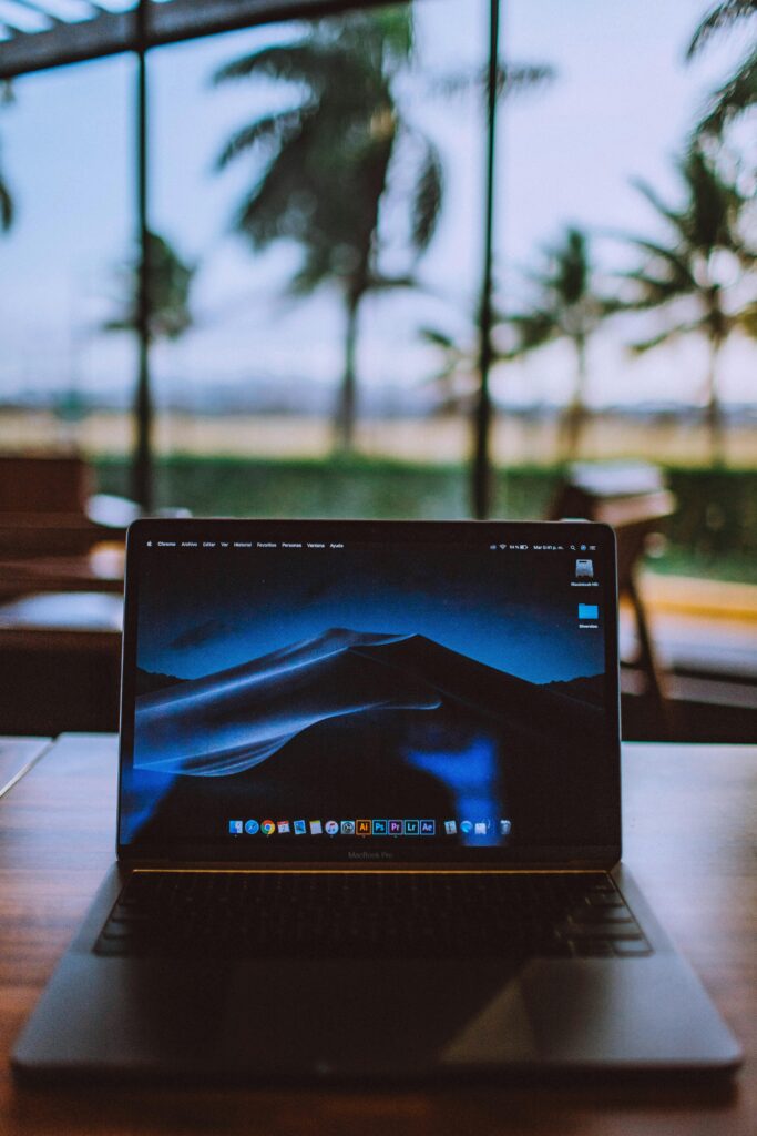 pexels-photo-2148216-2148216 A sleek laptop on a wooden desk with a tropical view behind, ideal for remote work and travel themes.