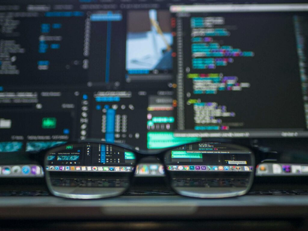pexels-photo-577585-577585 Eyeglasses reflecting computer code on a monitor, ideal for technology and programming themes.